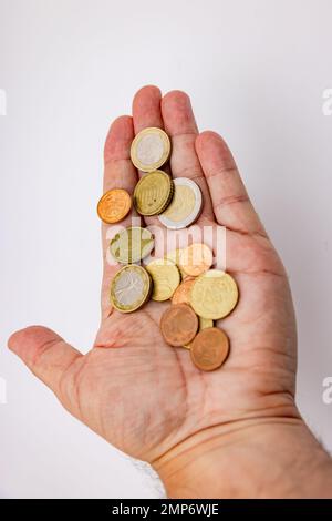 Detail oder Nahaufnahme einer Hand mit Euro-Münzen, die im Studio vor weißem Hintergrund isoliert wurden Stockfoto