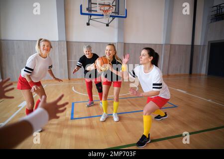 Frauen mit mehreren Generationen spielen im Fitnessstudio ein Basketballspiel. Stockfoto