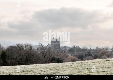 Blick auf den Kirchturm von Corfe Castle St Edwards Parish hinter Bäumen an einem Wintermorgen in Dorset, England, Großbritannien Stockfoto