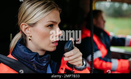 Porträt einer jungen Ärztin, die im Krankenwagen in ein Walkie-Talkie sitzt und spricht. Stockfoto