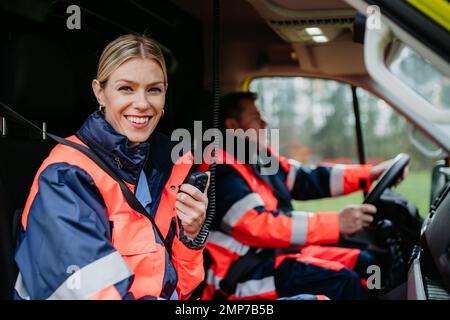 Porträt einer jungen Ärztin, die im Krankenwagen in ein Walkie-Talkie sitzt und spricht. Stockfoto