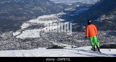 Garmisch Partenkirchen, Deutschland. 31. Januar 2023. Ein Skifahrer blickt von der Piste in das Loisach-Tal und auf die Häuser von Garmisch-Partenkirchen. Kredit: Angelika Warmuth/dpa/Alamy Live News Stockfoto