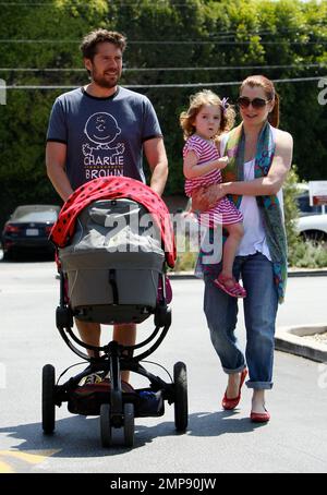 Die Schauspielerin Alyson Hannigan und ihre Familie verbringen den Tag gemeinsam im Brentwood Country Mart. Alyson fütterte ein Lama und spazierte später mit ihrem Mann Alexis Denisof, der die neue Tochter Keeva Jane Denisof in einem Kinderwagen schubste, und Tochter Satyana Marie Denisof, die sehr verspielt durch das Gras zu laufen schien. Los Angeles, Kalifornien. 15. Juli 2012 . Stockfoto