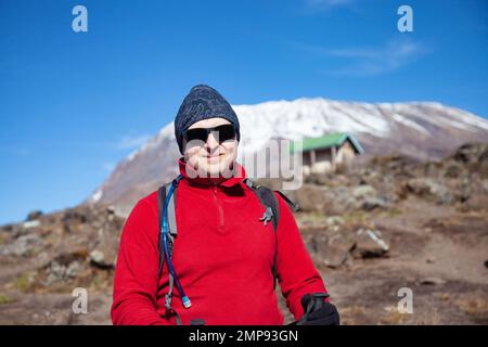 Männlicher Rucksacktourist auf der Wanderung zum Kilimandscharo-Berg. Stockfoto