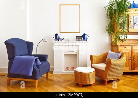 Innendesign-Vorlage des Wohnzimmers mit Modell-Poster-Rahmen über Kamin-Mantel, mit Flügel- und Rattanstuhl Vintage-Möbel und Pflanzen. Stockfoto