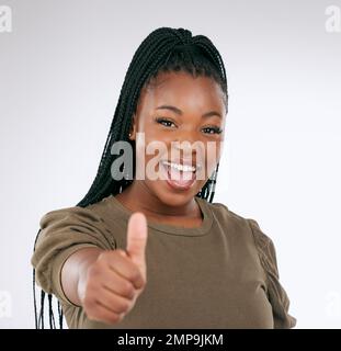 Schwarze Frau, Porträt lächelt und Daumen hoch für Sieg, Rabatt oder Deal isoliert auf grauem Studiohintergrund. Frohes afroamerikanisches weibliches Gesicht Stockfoto