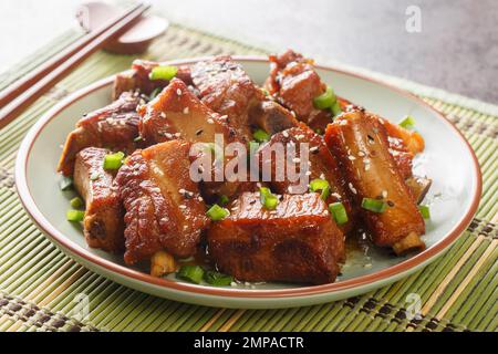 Glasierte Kurzrippchen aus Schweinefleisch in süßer und saurer Sauce in asiatischer Nahaufnahme auf einem Teller auf dem Tisch. Horizontal Stockfoto