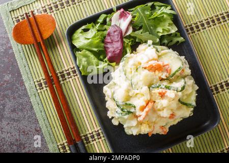 Japanischer Kartoffelsalat ist wie halb-Stampfkartoffeln gemischt mit Gemüse, Ei und Mayonnaise, Nahaufnahme auf einem Teller auf dem Tisch. Horizontale Draufsicht von Stockfoto