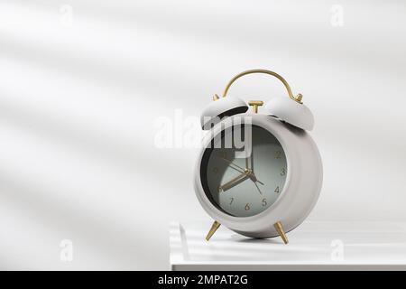 8:00am, minimalistischer grauer Wecker auf dem Holztisch und Morgenlicht. Stockfoto