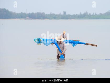 22. Januar 2023 - Chumphon Thailand Fischer fischen mit Netzen in flachem Wasser in der thailändischen See Stockfoto