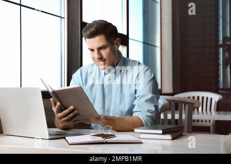 Ein Mann, der am Tisch im Café Hörbücher hört Stockfoto