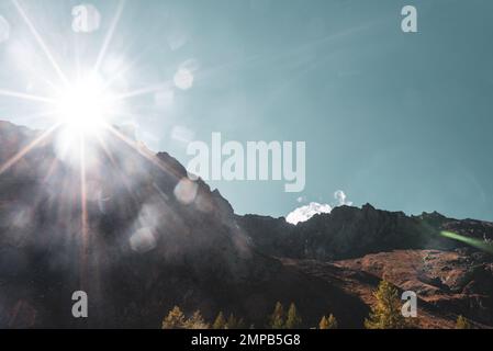 Die helle Sonne strahlt von hinter den Bergen in Altai in die Kamera. Stockfoto