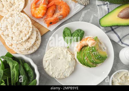 Gepuppter Reiskuchen mit Garnelen und Avocado, serviert auf einem grauen Marmortisch, flach liegend Stockfoto