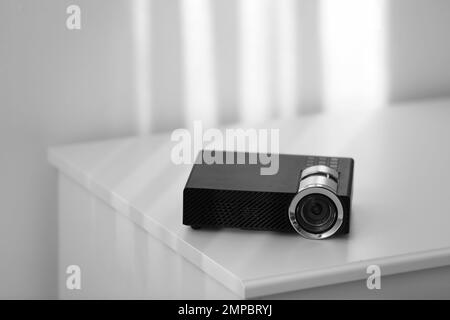 Moderner Videoprojektor auf weißem Tisch im Innenbereich Stockfoto