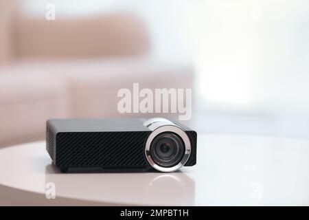 Moderner Videoprojektor auf weißem Tisch im Innenbereich Stockfoto