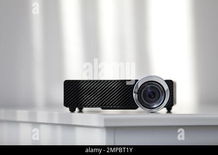 Moderner Videoprojektor auf weißem Tisch im Innenbereich Stockfoto