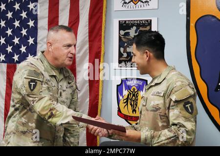 U.S. Army PFC. Antonio Mora, Spezialist für automatisierte Logistik, 92A, für Alpha Company, 449. Aviation Support Bataillon, 36. Combat Aviation Brigade, „Task Force Mustang“, 36. Infanterie Division (rechts), erhält Glückwünsche von Command Sgt. Maj. Robert W. Hartzog, Kommandofeldwebel Major der Task Force Mustang, während er sein Leistungszertifikat als „Held der Woche“ der Brigade während eines Befehls- und Mitarbeitertreffens im Hauptquartier der Task Force Mustang, Camp Buehring, Kuwait, am 12. Oktober 2022 erhielt. Mora, gebürtig aus Laredo, Texas, wurde für die Ausübung von Aufgaben außerhalb seiner pri anerkannt Stockfoto