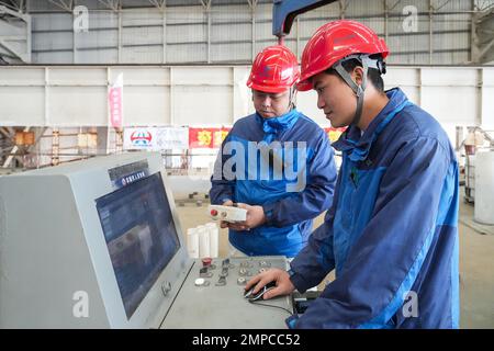 (230131) -- ZHUHAI, 31. Januar 2023 (Xinhua) -- Mitarbeiter manipulieren eine Maschine, um Beton in den Tauchschlauch E23 der Shenzhen-Zhongshan Autobahn Unterwassertunnel in einer Tauchrohrfabrik von CCCC Fourth Harbour Engineering Co., Ltd. Auf Niutou Island, Zhuhai, Südchina's Provinz Guangdong, 30. Januar 2023. Die Vorfertigung von E23, dem letzten Tauchrohr (nicht standardisiertes Rohr, einschließlich des letzten Gelenks) eines Unterwassertunnels, eines Abschnitts der Autobahn zwischen Shenzhen und Zhongshan in Guangdong, wurde am Dienstag abgeschlossen. Nach dem Gießen von Beton wird das 164,5 Meter lange Stahlrohr w Stockfoto