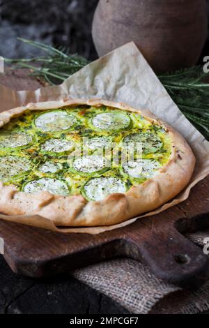 Hausgemachte Zucchini und Ziegenkäse Pie auf einem dunklen rustikalen Holzbrett Hintergrund. Rustikales Essen Stockfoto