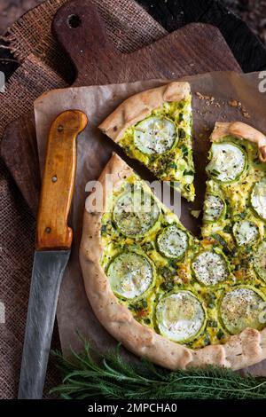 Hausgemachte Zucchini und Ziegenkäse Pie auf einem dunklen rustikalen Holzbrett Hintergrund. Rustikales Essen. Flach liegend, Draufsicht Stockfoto