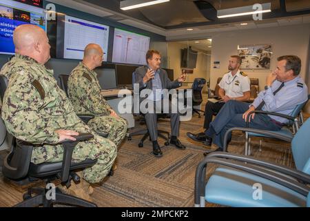 221012-N-RQ186-3009 NORFOLK, Virginia (12. Oktober 2022) Air Commodore Mike Baulkwill, Right, Kommandeur der britischen Kampfluftwaffe, hört, wie Dave Ferreira, der Direktor des MOC, das Maintenance Operation Center (MOC) Aircraft on Ground (AOG) mit der Führung des MOC während eines Besuchs am 12. Oktober erörtert. Die MOC AOG arbeitet daran, die Bemühungen zu bewerten, zu verbessern und angemessen zu organisieren, um einsatzfähige Flugzeuge vollständig einsatzbereit zu halten, wo immer die Navy sie benötigt. Air Commodore, CNAL, MOC, Vereinigtes Königreich, Wartung, Stockfoto