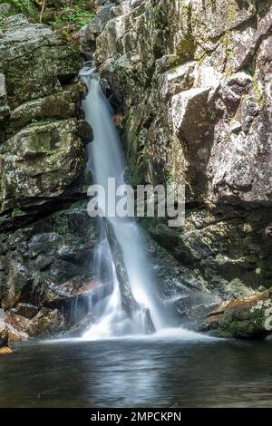 Eine vertikale Aufnahme eines Wasserfalls, der in wilder Natur von Klippen herunterfällt Stockfoto