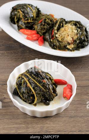 Buntil, gewürzte, gehackte Kokosnuss, Petai Cina und Sardellenfisch, verpackt mit Papaya- oder Kassava-Blättern. Stockfoto