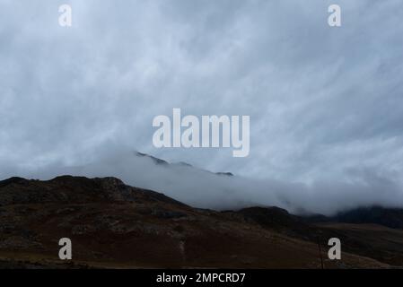 Dichter Nebel geht den Berg hinunter und lässt am Abend in Altai Schnee auf dem Gipfel nach sich selbst zurück. Stockfoto