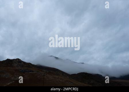 Dichter Nebel sinkt entlang des Berges und lässt Schnee auf dem Gipfel hinter sich in Altai zurück. Stockfoto