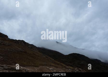 Dichter Nebel fällt entlang des Berges und lässt im Herbst in Altai Schnee nach sich ziehen. Stockfoto