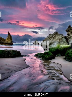 Sonnenaufgang am Strand mit kleinem Bach in Bandon, Oregon Stockfoto