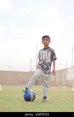 Karatschi Pakistan 2019, ein Kind, das am Sonntagmorgen mit seinem blauen Fußball für ein Foto posiert, asiatische Kinder, lokale Sportarten, Fußball in Pa Stockfoto