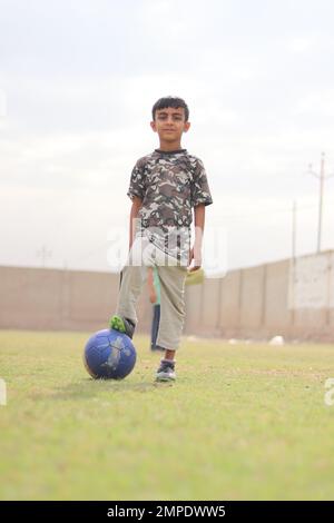 Karatschi Pakistan 2019, ein Kind, das am Sonntagmorgen mit seinem blauen Fußball für ein Foto posiert, asiatische Kinder, lokale Sportarten, Fußball in Pa Stockfoto