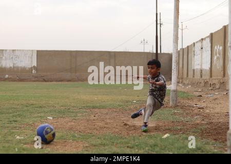 Karatschi Pakistan 2019, ein Kind, das am Sonntagmorgen auf dem Fußballplatz einen Fußball tritt, asiatische Kinder, lokale Sportarten, Fußball in pakistan, Outdoor-aktivitäten Stockfoto