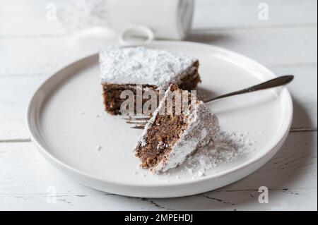 Italienische Schokolade, Mandelkuchen, Torta Caprese, serviert auf einem weißen Teller mit Gabel. Nahaufnahme und Vorderansicht Stockfoto