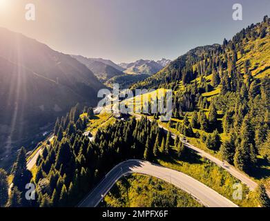 Wunderschöne Berglandschaft mit Schneeglöckner und Straße und Fluss am Sonnenaufgang in Almaty, Kasachstan. Outdoor- und Wanderkonzept, Luftdrohne Stockfoto
