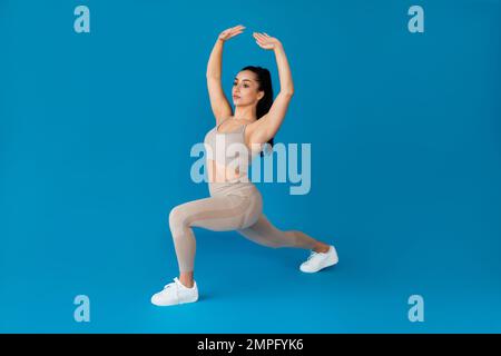 Ganzkörper junge sportliche Fitnesstrainerin, die auf Blau trainiert Stockfoto