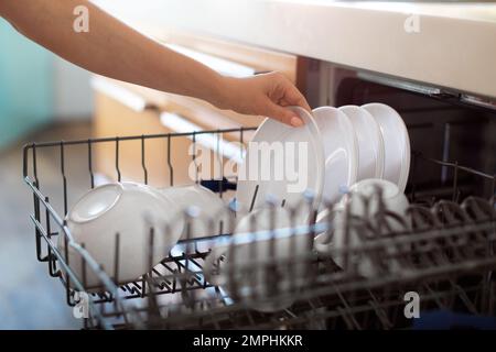 Eine Unbekannte Frau, Die Sauberes Geschirr Aus Der Spülmaschine In Der Küche Ablädt Stockfoto