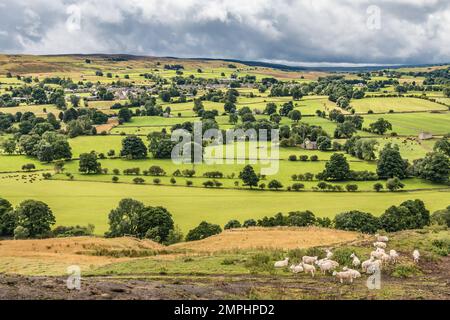 Das Teesdale Dorf Mickleton in starker Sonne während einer kurzen Pause in der dunklen Wolkendecke, wie von Whistle Crag aus gesehen. Stockfoto