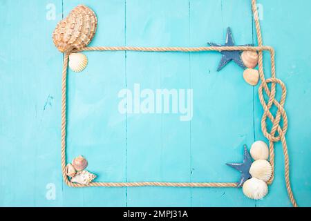 Juteseilrahmen mit Knoten, Muscheln und Sternen auf blauen Acrylholzbrettern. Stockfoto