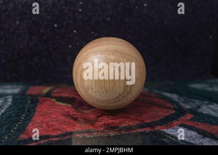 Holzkugel auf dunklem Samthintergrund, Nahaufnahme mit weichem Fokus Stockfoto