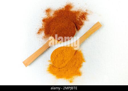 Zwei Holzlöffel mit Kurkuma und geräucherter Paprika auf weißem Hintergrund Stockfoto