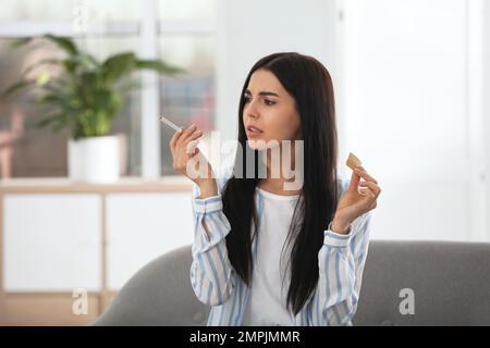 Emotionale junge Frau mit Nikotin-Pflaster und Zigarette zu Hause Stockfoto