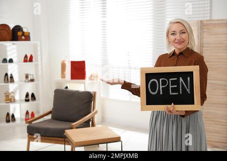 Weibliche Geschäftsinhaberin mit OFFENEM Schild in einer Boutique. Platz für Text Stockfoto