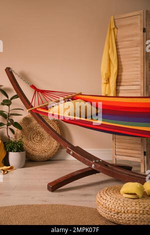Farbenfrohe Hängematte mit Kissen in moderner Zimmereinrichtung Stockfoto