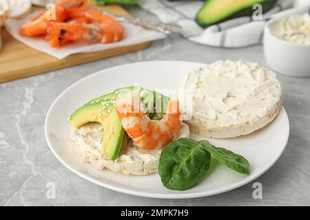 Gepuppter Reiskuchen mit Garnelen und Avocado auf einem grauen Marmortisch Stockfoto