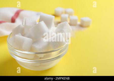 Raffinierte Zuckerwürfel in einer Glasschüssel auf gelbem Hintergrund Stockfoto