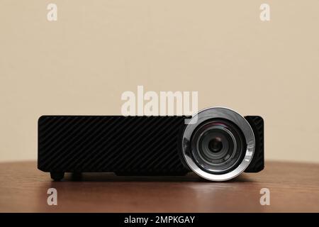 Moderner Videoprojektor auf Holztisch vor beigefarbenem Hintergrund Stockfoto