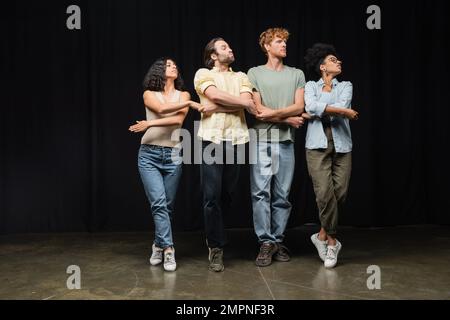 Die ganze Länge junger interrassistischer Schauspieler, die kleine Schwäne in der Schauspielschule üben Stockfoto