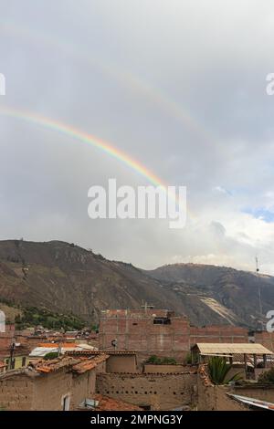Doppelter Regenbogen am Nachmittag mit Blick auf einige Häuser aus lehmziegeln und Ziegelsteinen, Berge und Himmel, aufgenommen am Nachmittag in Caraz. Stockfoto